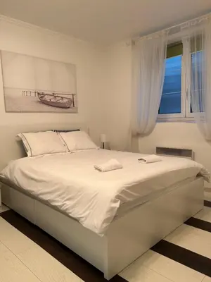a white bed in a white bedroom with a window at Lana apartman in Belgrade
