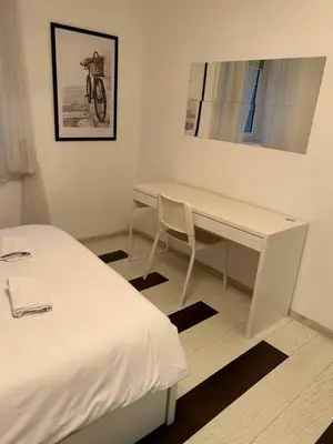 a white desk with a chair next to a bed at Lana apartman in Belgrade