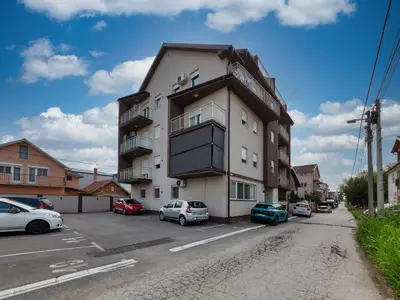 a building with cars parked in a parking lot at Nobless in Belgrade