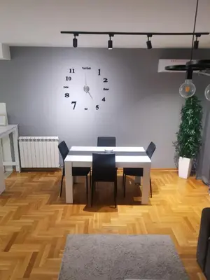 a dining room with a table and a clock on the wall at Nobless in Belgrade