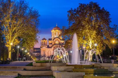 a building with a fountain in front of it at night at APARTMAN KRUNA in Belgrade