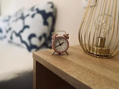 a alarm clock sitting on a table next to a bed at Cozy Trg in Lazarevac