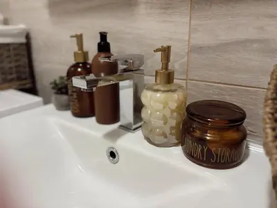 a bathroom sink with bottles of honey on it at Cozy Trg in Lazarevac