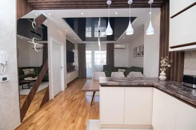 a kitchen with white cabinets and a living room at Hemingway LUX in Arandjelovac