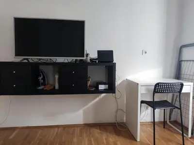 a black entertainment center with a tv on a wall at Quiet city center oasis - In the shade of walnut in Belgrade
