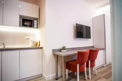 a kitchen with a table and two red chairs at Coral Studio in Batajnica
