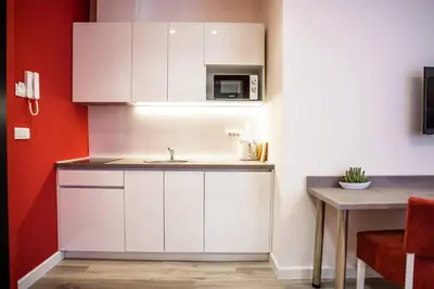 a kitchen with white cabinets and a sink and a table at Coral Studio in Batajnica