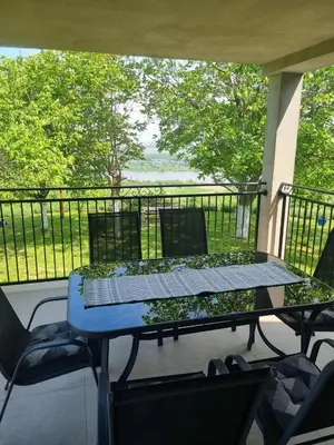 a table and chairs on a balcony with a view of the water at Casa Horizont in Slankamenački Vinogradi