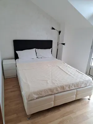 a white bed in a bedroom with a white wall at Apartmani MilaMi #3 in Kalugjerica
