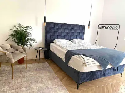 a bedroom with a blue bed and a chair at Soba 23 in Belgrade