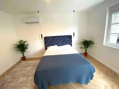 a bedroom with a blue bed and two potted plants at Soba 23 in Belgrade