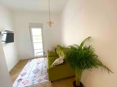 a green couch in a living room with a plant at Soba 23 in Belgrade