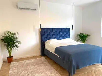 a bedroom with a blue bed and two plants at Soba 23 in Belgrade
