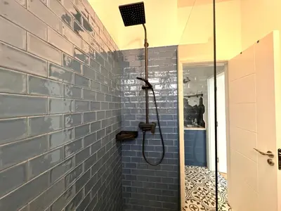 a shower in a bathroom with a blue brick wall at Soba 23 in Belgrade