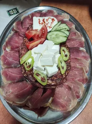 a plate of food with meat and cheese and vegetables at Zmaj Ognjeni Etno Concept in Kupinovo