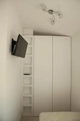 a bedroom with a tv and a white cabinet at Apartman Cookie Kolačić blizu aerodroma Nikola Tesla in Dobanovci