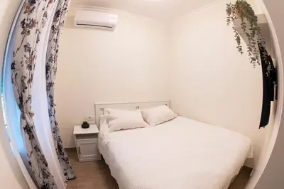 a small bedroom with a white bed and a window at Pop luxury apartments in Belgrade