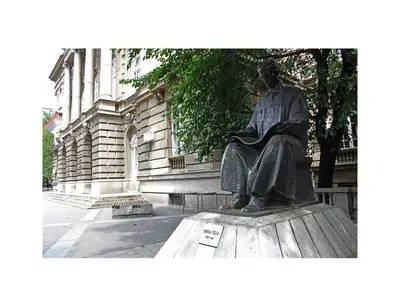 a statue of a man sitting in front of a building at Serene Bulbuder Suite in Belgrade