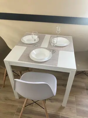 a white table with two plates and wine glasses on it at Apartman Jany in Kijevo