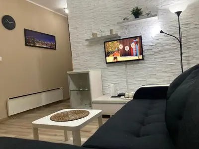 a living room with a couch and a tv on a brick wall at Apartman Jany in Kijevo