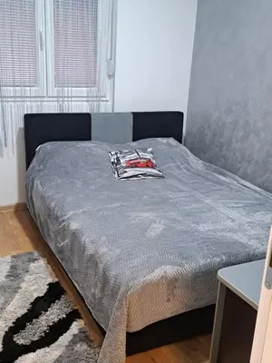 a bedroom with a bed with a blue comforter at Apartman Sara 2 in Novi Grad