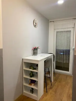a white table with a shelf and a clock on a wall at Apartman Sara 2 in Novi Grad