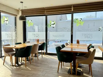a restaurant with wooden tables and chairs and windows at H.T Hotel in Belgrade