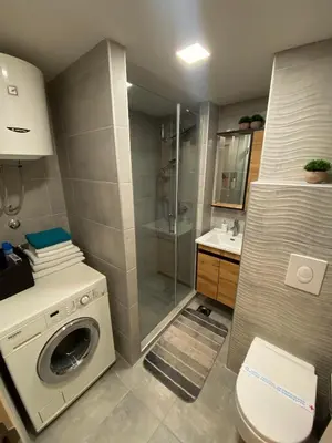 a bathroom with a washing machine and a shower at Apartman ANN II in Pančevo