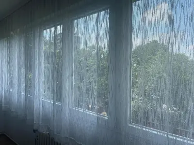 a window with white curtains in a room at Apartman Pupin in Belgrade