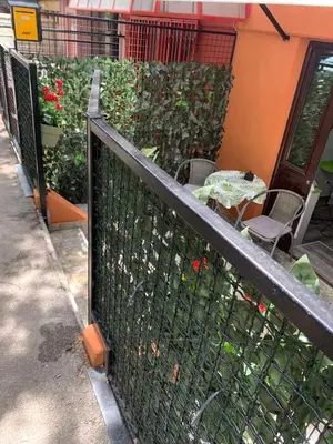 a fence next to a patio with a table and flowers at Apartman Lara in Belgrade