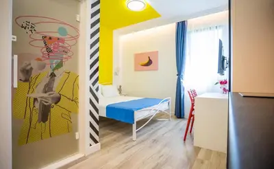 a small room with a bed and a bedroom with yellow at Studio Pop Art in Batajnica