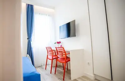 a room with a table with red chairs and a tv at Studio Pop Art in Batajnica
