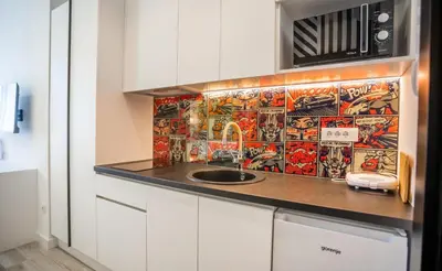 a kitchen with a sink and a tile wall at Studio Pop Art in Batajnica