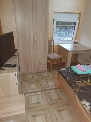 a room with wooden floors and a desk and a television at Small cute doublebed room A4 in Pančevo in Pančevo