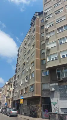a tall building with cars parked in front of it at Apartman Central Place in Belgrade