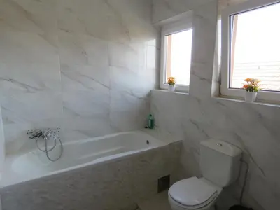 a white bathroom with a tub and a toilet at Apartments Bella Mare Belgrade in Belgrade