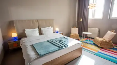a bedroom with a large bed and two chairs at Avangarda Suites in Belgrade