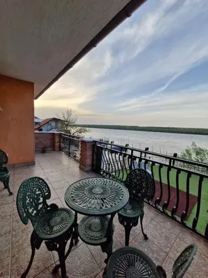 a balcony with tables and chairs and a view of the water at Vila Soleil in Smederevo
