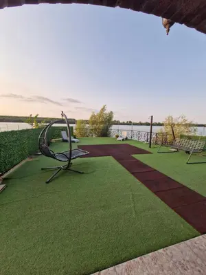 a park with benches and grass and a body of water at Vila Soleil in Smederevo