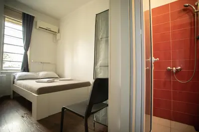 a small room with a bed and a chair at All in Hostel in Belgrade
