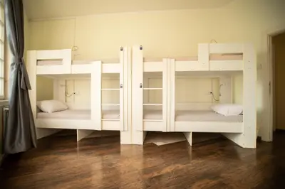 two white bunk beds in a room with wood floors at All in Hostel in Belgrade