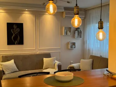 a dining room with a table and chairs and lights at Apartman Marija in Zvezdara