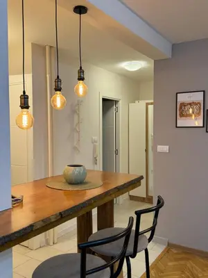 a dining room with a table and chairs and lights at Apartman Marija in Zvezdara