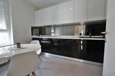 a kitchen with white cabinets and a table and chairs at A blok - One bedroom apartment in Belgrade