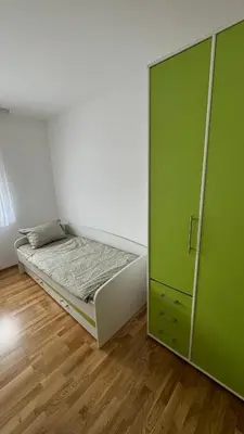 a bedroom with a bed and a green cabinet at JR Lux apartman in Stara Pazova