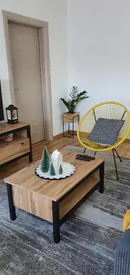 a coffee table in a living room with a yellow chair at JR Lux apartman in Stara Pazova