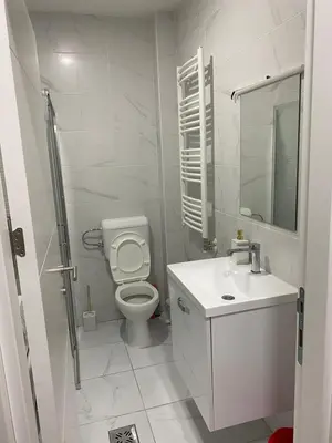 a white bathroom with a toilet and a sink at Apartman Popović in Ruma