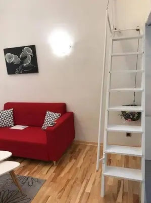 a living room with a red couch and a white ladder at Apartman 4 you Downtown in Belgrade