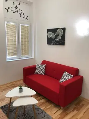 a red couch in a living room with a table at Apartman 4 you Downtown in Belgrade