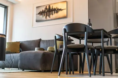 a dining room with black chairs and a couch at Apartments Royal - Sakura Park in Novi Beograd